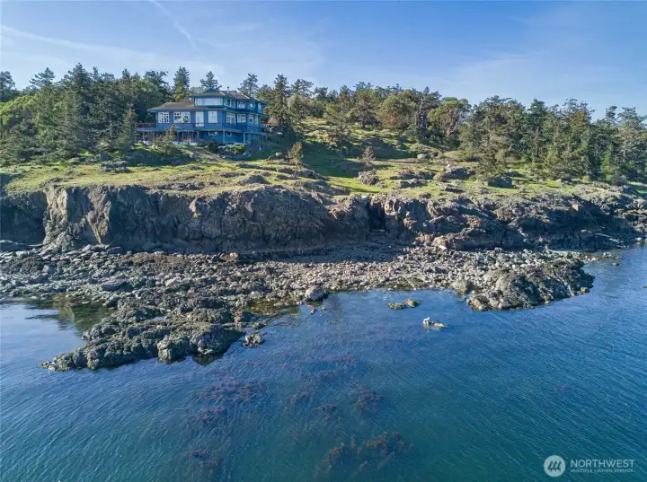 Privately perched above the shoreline, this striking waterfront residence showcases its commanding position on a rare point surrounded by water.