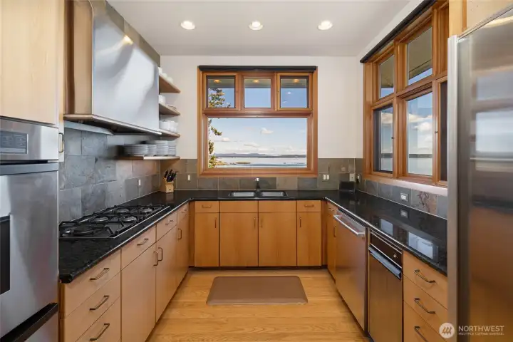 Chef’s kitchen with sleek cabinetry, stone surfaces, and premium appliances, perfectly positioned to take in stunning water views while cooking and gathering.