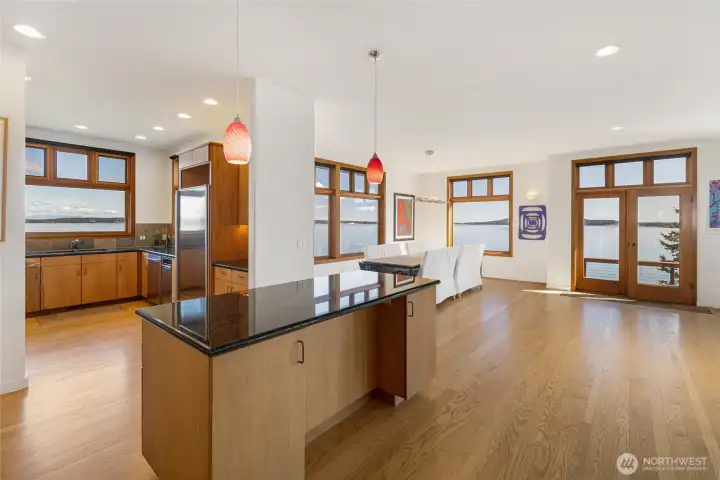 Open-concept kitchen and dining area with expansive island and seamless flow to the outdoors, ideal for entertaining against a backdrop of endless water views.