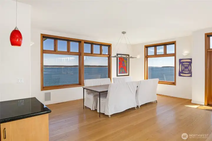 Elegant dining area framed by expansive windows, offering panoramic waterfront views—an exceptional setting for everyday dining and entertaining on San Juan Island.