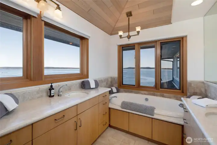 Spa-inspired primary bath featuring soaking tub, dual vanities, and serene water views—designed for relaxation with a connection to the outdoors.
