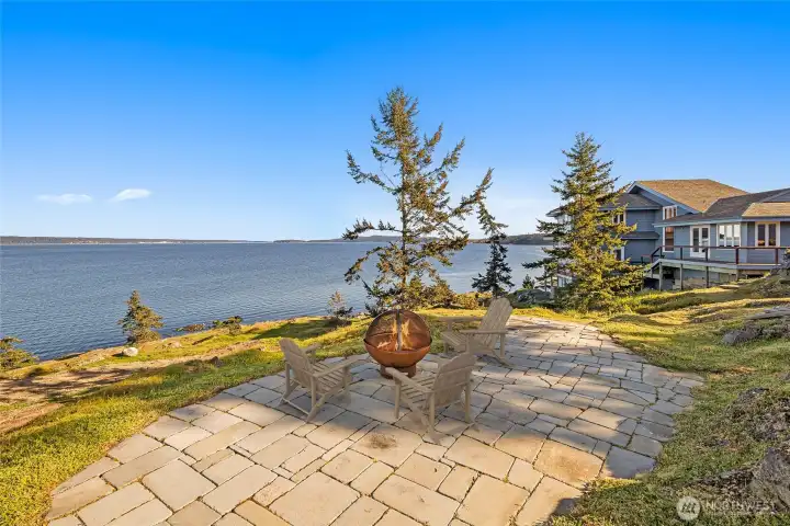 Private bluff-top setting with stone pathways and fire feature, offering a serene place to unwind while taking in expansive waterfront views and island sunsets.