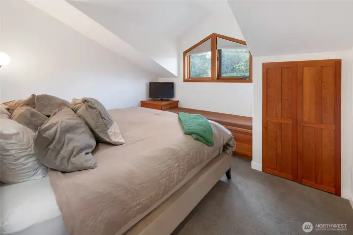 Inviting bedroom with soft natural light and built-in storage, offering a comfortable and private retreat tucked beneath vaulted lines.