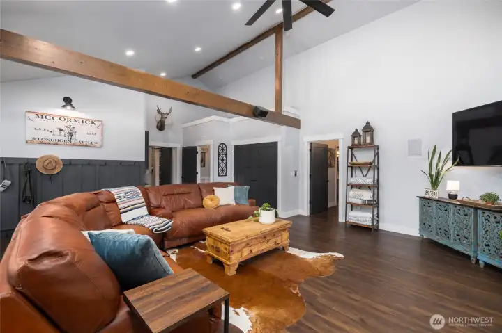 Walking back through to the addition, rustic beams, LVP floors and ceiling fan grace this well thought-out space. Door to primary bedroom on the right, powder room and huge closet are in center of photo.