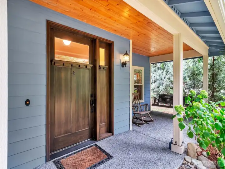Expansive covered wrap around front porch with a dramatic front door.