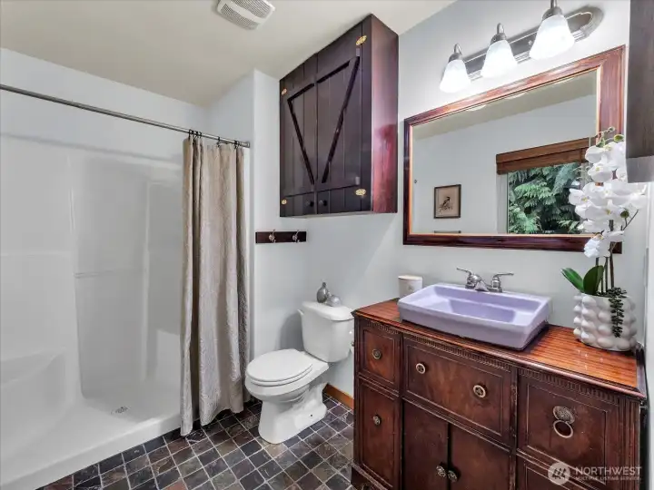 Primary bathroom includes slate tile floors and an eclectic sink vanity.