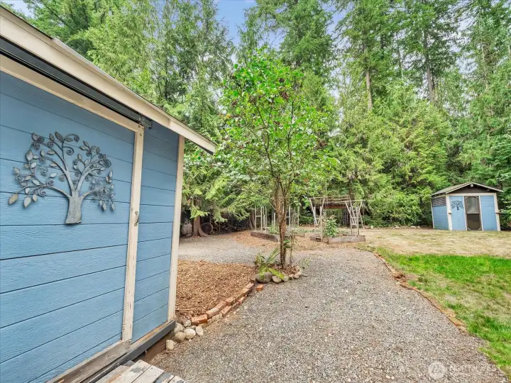 Fully Fenced back yard with two storage buildings, raised bed gardens, fire pit  and a tree fort. Lovely evergreen at much of the perimeter of the lot for a sense of privacy.