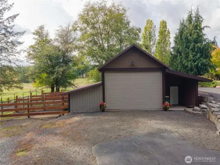 Front view of barn with large roll up door, as well as a covered patio area with man door.