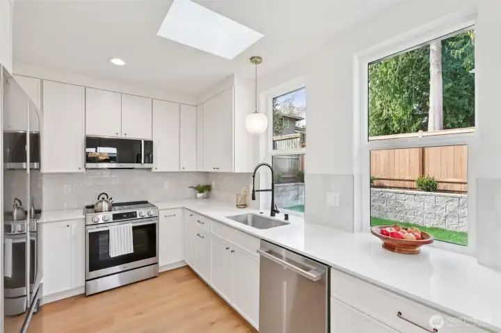 Beautiful kitchen with quartz, wood floors, stainless appliances and copper details