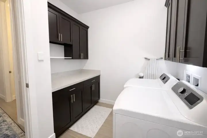 Laundry room with generous storage, cabinets, counter top for folding clothes and quality washer and dryer convey (transfers ownership) with sale.