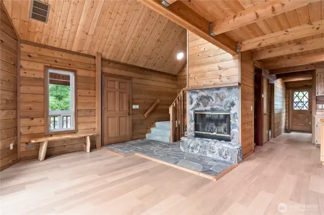 View to the front entryway and the back entry as well. The back door is also solid wood. The custom wood fireplace is central to this home, stone flooring and fireplace.