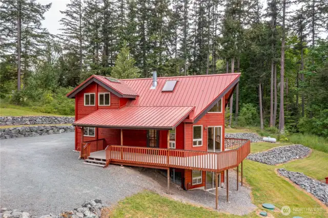 A wonderful view of the spacious driveway, and immaculate landscaping, with multiple rock terraces. The metal standing seam roof adds beauty and charm to this beautiful home.