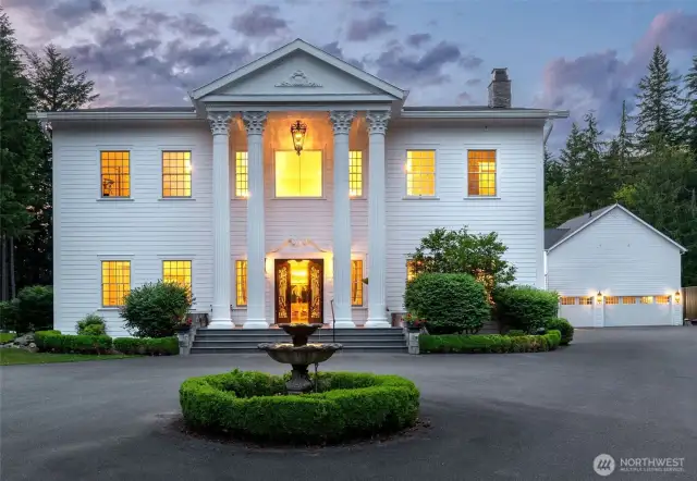 A stone fountain leads to grand glass-and-iron doors and a dramatic entryway.