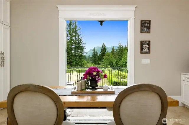 The breakfast area nestled within the kitchen offers breathtaking views of Mount Si, visible through double French doors that open to a covered patio—seamlessly blending indoor comfort with outdoor entertaining in every season.