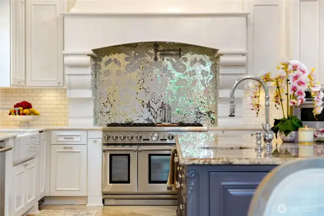 Anchoring the culinary space is a professional-grade 48” propane Thermador range with dual ovens, six burners, and an interchangeable griddle/grill, framed by a custom 60” Thermador hood and a glass-and-marble mosaic backsplash that adds a luxurious focal point. The walk-in pantry provides expansive, well-organized storage to support your culinary endeavors.