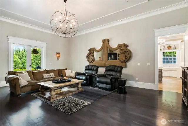 To one side of the atrium, rich dark Brazilian cherry wood floors lend warmth and sophistication to the formal living room, creating an inviting atmosphere that balances timeless elegance with everyday comfort. Sunlight dances through expansive windows, while carefully crafted architectural details add a sense of refinement.