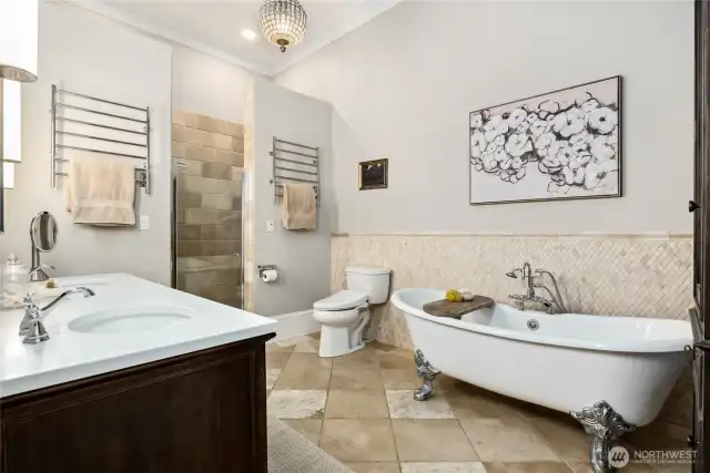 The spa-inspired primary bathroom is a haven of relaxation, complete with an oversized clawfoot soaking tub (fits 6’ 7” height comfortably), travertine tiles, a glass-enclosed shower with double rain shower heads and hand wand, dual towel warmers for added comfort, a Toto Washlet bidet toilet seat and a newly updated, marble-topped, double vanity that blends style with function.
