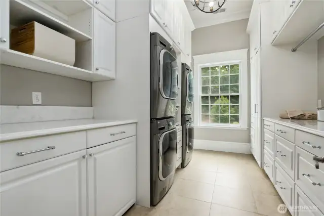The spacious laundry room is equally impressive, equipped with dual stacked LG washer and dryer units, Italian marble countertops, an MTI sink with whirlpool jets made specifically for handwashing, a roll-out ironing board, roll-out shelves, built-in laundry hamper drawers, large hanging and folding spaces and two hidden rolling laundry carts that simplify laundry day. Ample storage throughout provides generous room for linens, extra bedding, pillows, toiletries, and towels—keeping everything neatly organized and within easy reach.