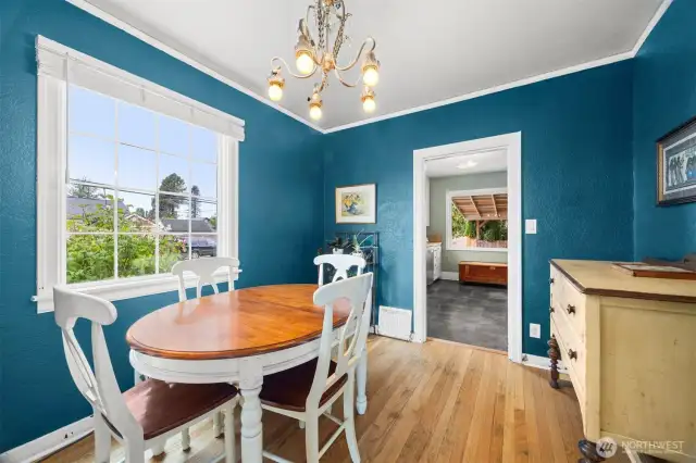 Dining room looking into the kitchen. This bright area has a beautiful accent color and wonderful rich wood floor.