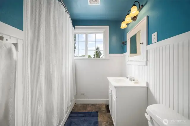 Bathroom upper level, has a bathtub shower combo.  Great feature of a window that opens to allow light and fresh air when you want it.  Enjoy the rich classic blue & white motif with wainscotting accents