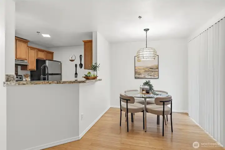 Bright dining space with hardwood floors, a woven pendant light, and a seamless connection to the kitchen — perfect for everyday meals or casual entertaining.