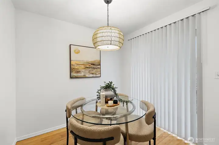 Sunlit dining nook with hardwood floors, a statement pendant fixture, and sliding panel access, creating a warm and inviting space.