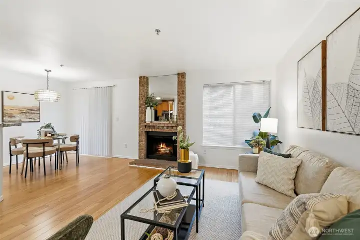 Generous living room with a brick fireplace, hardwood floors, and open sightlines to the dining area — great for relaxing or hosting.