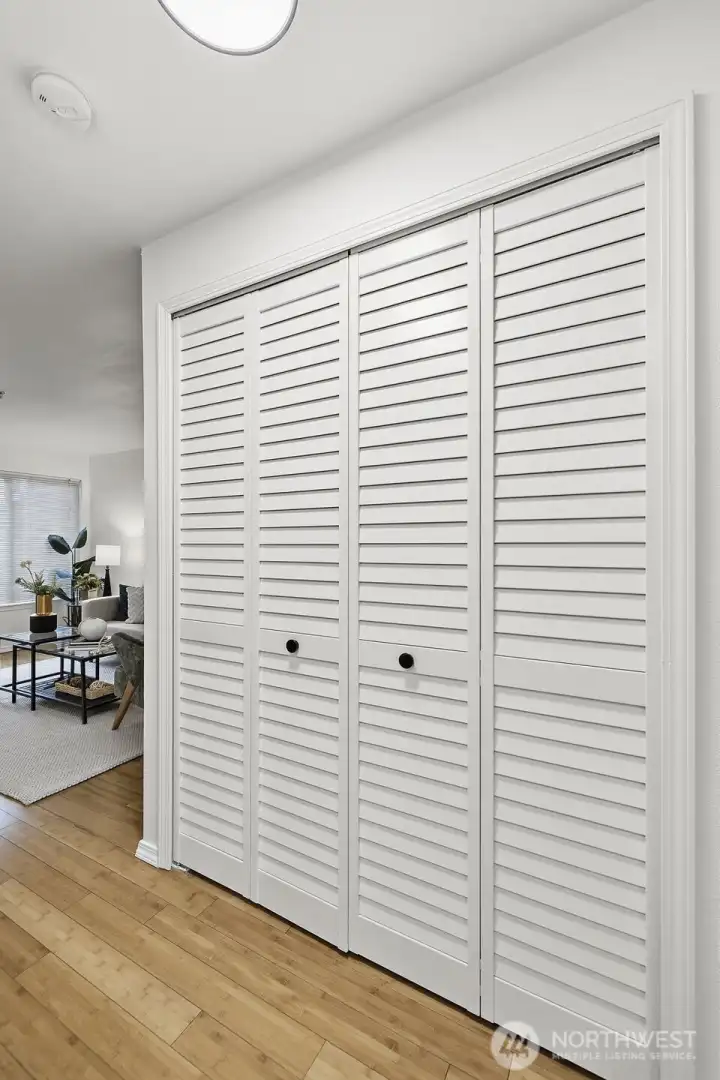 Full-wall louvered closet doors conceal the in-unit washer and dryer — a rare and convenient feature.