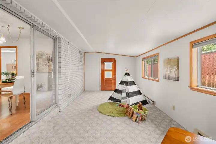 This enclosed room likely started as a patio, and it’s easy to see how it connects to the outdoors with doors at each end. Here you’re looking toward the west-facing door, which brings in light and makes the space feel open and connected.