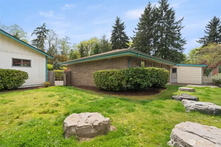 The decorative rock features thoughtfully cover the septic lids, blending them into the landscape. The open gate leads through to the garage and driveway for easy access.