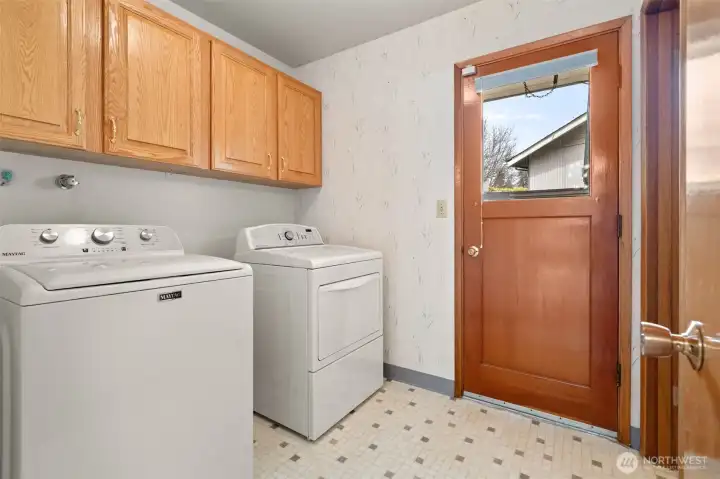 The laundry room is in a perfect location with direct access to the backyard, and convenience with direct access to the backyard, and it also connects to a third bathroom just beyond.