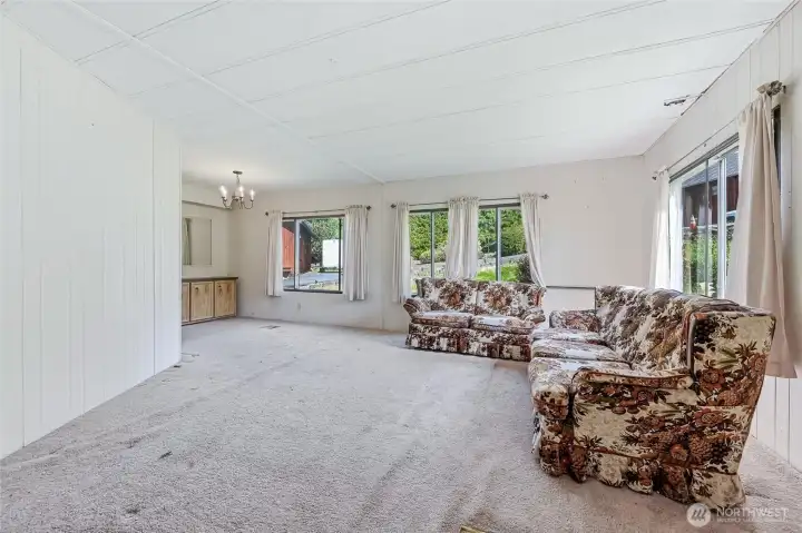 View of Family Room. Windows are not in great condition, many with cracks and damage to the window ledges. please note the hole in the ceiling just above the front window. The roof was replaced 8-10 yrs ago, but the ceiling was never repaired. Seller is selling as-is and will make no repairs or concessions for repairs.