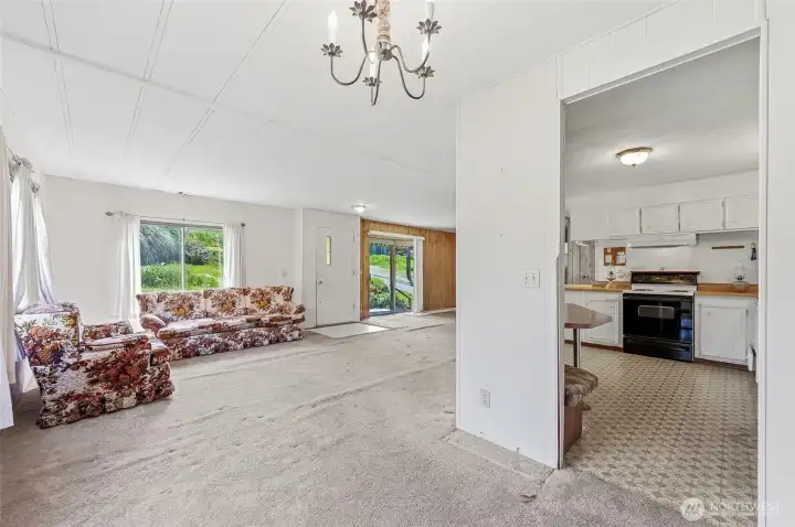 View from dining room toward family room and entry. Good view of the kitchen with built-in banquet. *There are items inside some of the kitchen cabinets that will remain with the home.
