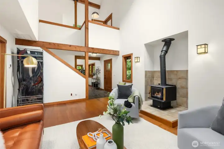 Comfortable living room featuring vaulted ceilings, exposed beams, and a cozy wood stove.
