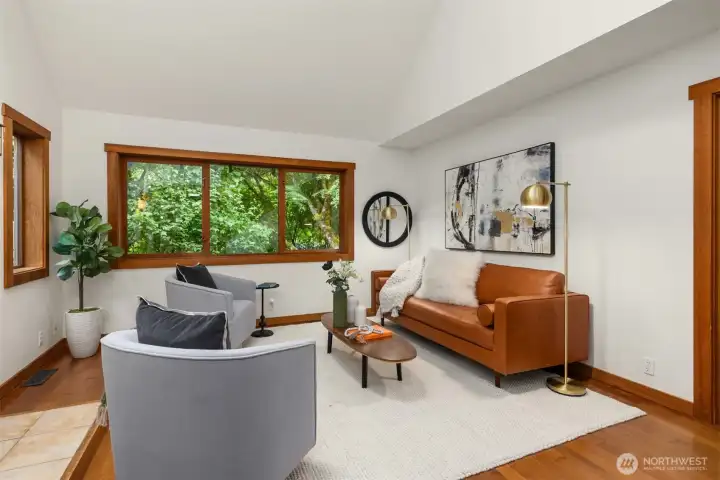 Comfortable living room featuring vaulted ceilings, exposed beams, and a cozy wood stove.