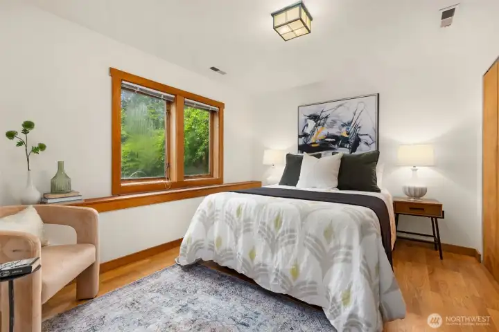Serenebedroom with large windows framing peaceful forest views.