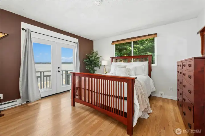 The Primary bedroom is anchored by French doors that open to a private water-view deck.