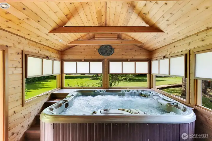 A cedar-lined spa room creates a calm, Zen-like retreat, with a bubbling hot tub framed by warm wood, natural light, and peaceful views of the grounds. Designed for restoration and quiet, the space feels equal parts wellness sanctuary and private escape.