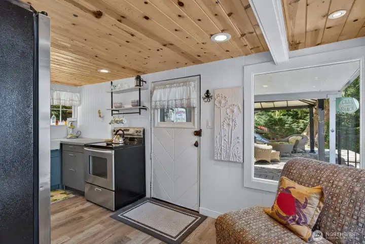 Bright and inviting kitchen with stainless steel appliances, LVP flooring and warm wood ceilings.