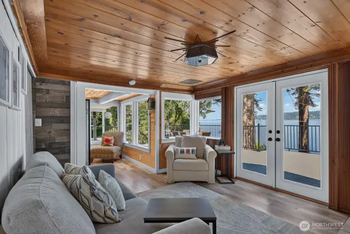 Cozy waterfront living room featuring panoramic bay views, an open layout, and seamless indoor-outdoor living through French doors.