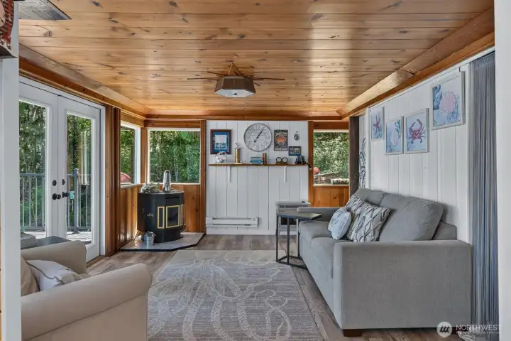 The open-concept living room blends rustic cabin charm with modern comfort, complete with a pellet stove and abundant natural light.