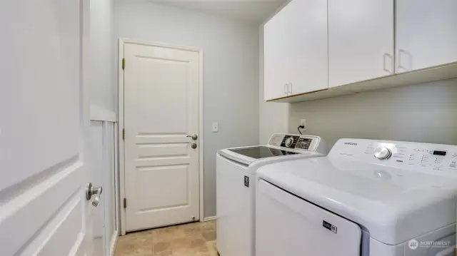 The utility room is close to the kitchen and has cabinets and vinyl flooring.  The washer and dryer remain with the home.  The access to the garage is through the far door.