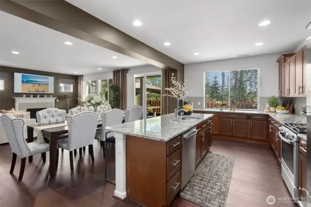 Enjoy the warm ambiance created by recessed lighting, rich hardwood floors and cabinetry, while oversized windows bring in natural light and offer views of the lush greenery outside.