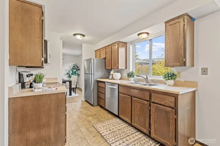 The kitchen features lots of cabinet space, stainless steel double sinks, and easy to maintain countertops. Notice the counter to ceiling window above the kitchen sinks that look out to the back gardens!