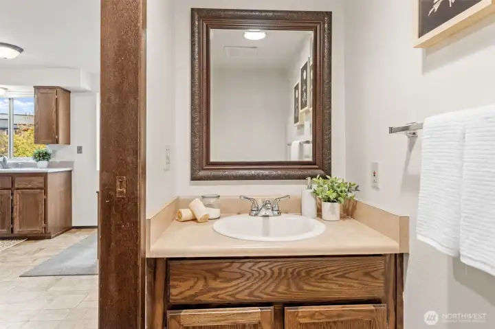 Conveniently located near the kitchen, this half bath includes solid wood cabinetry and durable hard surface countertops. A framed mirror and neutral finishes complete the space.