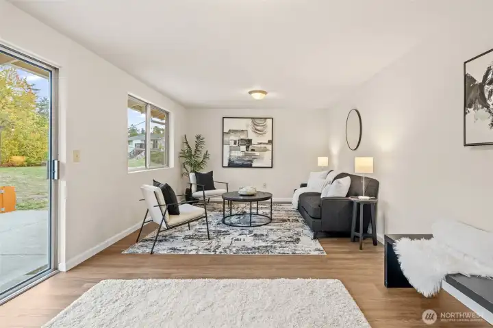 The family room features a sliding glass door that opens to the backyard, making indoor-outdoor entertaining effortless. Large windows and updated flooring complete this bright and functional space. Notice the laminate flooring here as well.