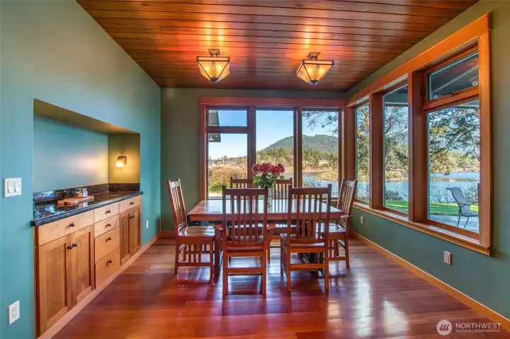Main house dining area showcases the views into Eastsound Village, Indian Island and Buck Mountain. Built-in custom cabinet for easy entertaining. This is just off the kitchen living area. Covered patio outside windows.