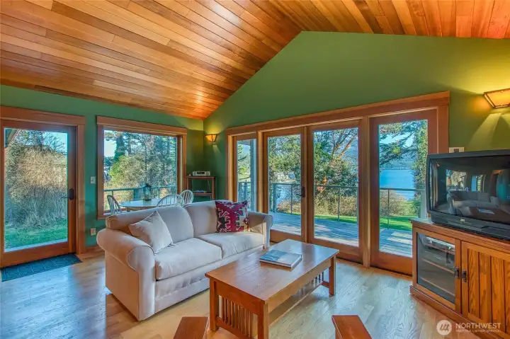Guest house living space is finished with oak flooring, custom fir cabinets and vaulted ceiling. The space mirrors the main house with large windows, natural light and views across East Sound Bay,