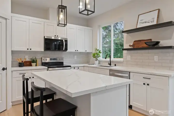 Kitchen has island with quartz countertop, extra seating and storage.