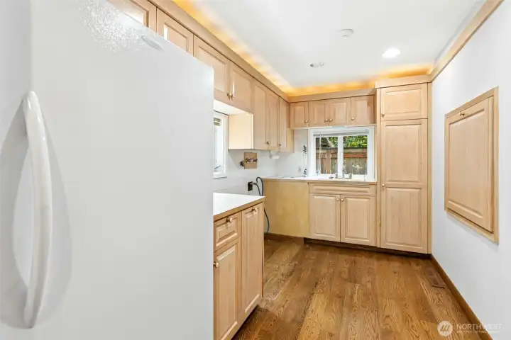 Butler's pantry to the back of the kitchen provides an additional freezer, washer / dryer hook-ups, Trash / recycling chute accessed from outside of home, built-in fold-out worktable (square to right), up-lighting & (not shown in the photo) built in ironing board.